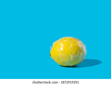 Concept Art Of Yellow Lemon Fruit Wrapped In Clear Packing Tape On High Contrast Blue Background