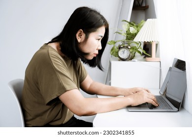 concept of Asian woman with Kyphosis: side view of laptop Work with hunched back, forward head posture, and spinal curvature