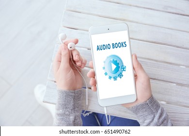 Concept of audio books and modern technology. Woman using smartphone and earphones, closeup