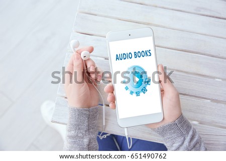 Concept of audio books and modern technology. Woman using smartphone and earphones, closeup