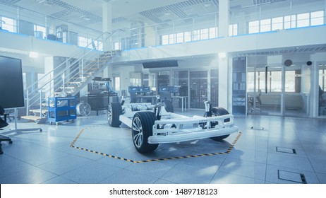 Concept Of Authentic Electric Car Platform Chassis Prototype Standing In High Tech Industrial Machinery Design Laboratory. Hybrid Frame Include Tires, Suspension, Engine And Battery.