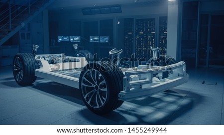 Concept of Authentic Electric Car Platform Chassis Prototype Standing in Industrial Machinery Design Laboratory. Hybrid Axel Frame include Wheels, Suspension, Engine, Brakes and Battery.