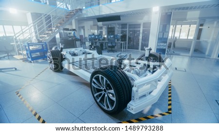 Concept of Authentic Electric Car Platform Chassis Prototype Standing in High Tech Industrial Machinery Design Laboratory. Hybrid Frame include Tires, Suspension, Engine and Battery.