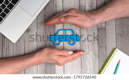 Concept of auto insurance with hands in a protective gesture