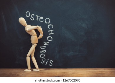 Concept of back pain. A wooden figure depicts a pain in the back. The inscription on a chalkboard osteochondrosis. - Powered by Shutterstock