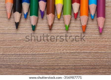 Concept back to school - frame of multicolored pensils on wood background