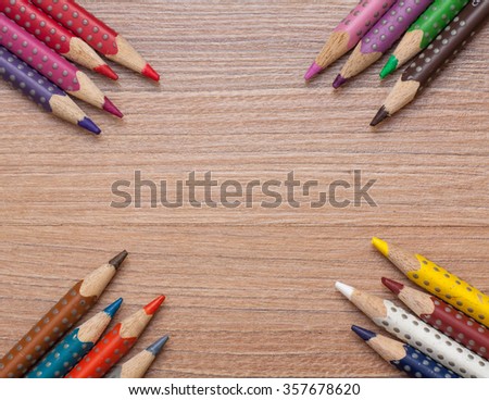 Concept back to school - frame of multicolored pensils on wood background