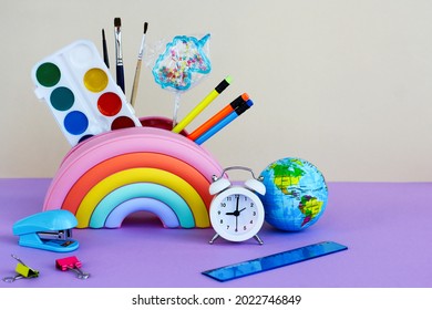 the concept of back to school, time to learn, diversity and inclusivity. pencil case in the form of a bright rainbow with a unicorn-shaped lollipop