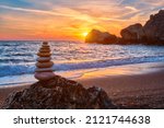 Concept of balance and harmony. Cairn stack of stones pebbles cairn on the beach coast of the sea in the nature on sunset. Meditative art of stone stacking