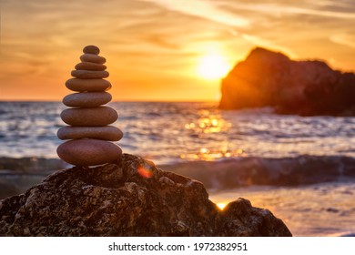 Concept of balance and harmony. Cairn stack of stones pebbles cairn on the beach coast of the sea in the nature on sunset. Meditative art of stone stacking - Powered by Shutterstock