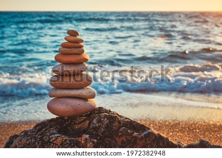 Concept of balance and harmony. Cairn stack of stones pebbles cairn on the beach coast of the sea in the nature on sunset. Meditative art of stone stacking