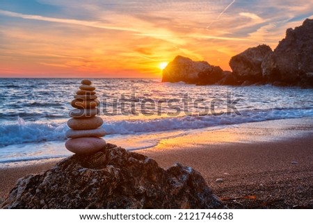 Concept of balance and harmony. Cairn stack of stones pebbles cairn on the beach coast of the sea in the nature on sunset. Meditative art of stone stacking