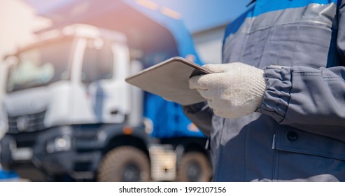 Concept banner automated logistics online internet. Dump truck driver man in uniform with tablet computer controls loading of cargo or coal.