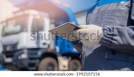 Concept banner automated logistics online internet. Dump truck driver man in uniform with tablet computer controls loading of cargo or coal.