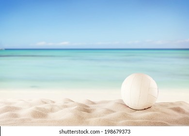 Concept of beach volleyball with ball on sand, blur sea as background
