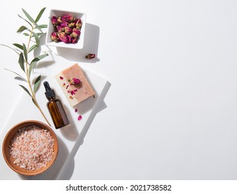 Concept  beauty home  spa  with cosmetic products peeling natural soap, mineral salt, oil and dry roses on white background. Top view  and copy space image