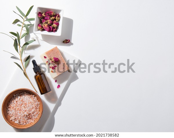 Concept  beauty home  spa  with cosmetic\
products peeling natural soap, mineral salt, oil and dry roses on\
white background. Top view  and copy space\
image