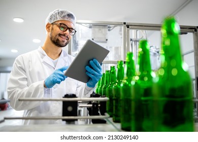 Concept of beer production. Factory worker controlling quality of beer beverage production in bottling factory on conveyor machine. - Powered by Shutterstock