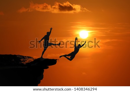 The concept of betrayal and the help of friends, Silhouette of Men are jumped between high cliff at a red sky sunset background