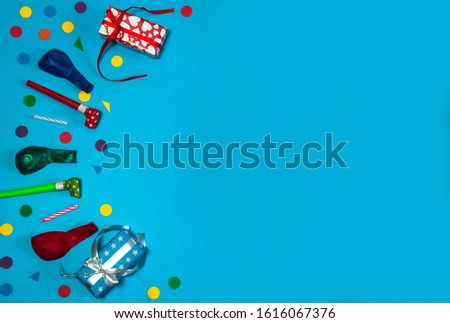 The concept of birthday. A border of gift boxes, balloons, confetti, cake candles and blowouts on a light blue background. Free space.