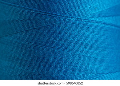 concept of the blue bobbin of thread close up, macro. sewing background. top view. flat lay. Close up blue thread texture.