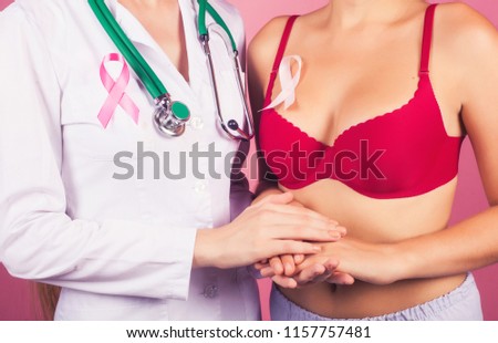 The concept of breast cancer: the doctor holds the patient's hand as a sign of support in the fight against cancer. Pink Ribbon.