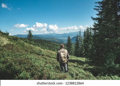 Concepto de viaje y aventura impresionantes. Largo retrato lateral de un joven disfrutando de la naturaleza mientras camina sobre una colina verde de montañas Foto de stock