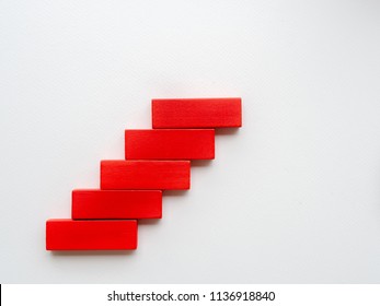 Concept of building success foundation. Women hand put red wooden block in the shape of a staircase