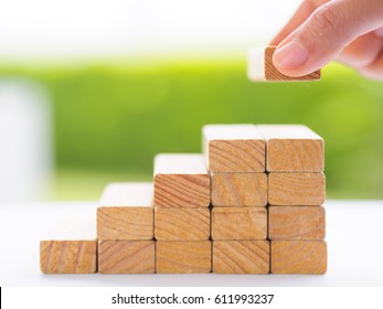 Concept Of Building Success Foundation. Women Hand Put Wooden Blocks In The Shape Of A Staircase