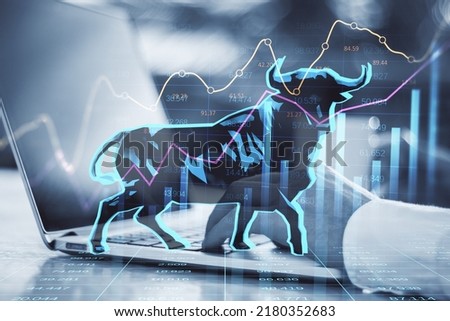 Concept of bullish market. Close up of businessman hands using notebook keyboard with glowing bull hologram over forex chart on blurry background. Trade and invest concept. Double exposure