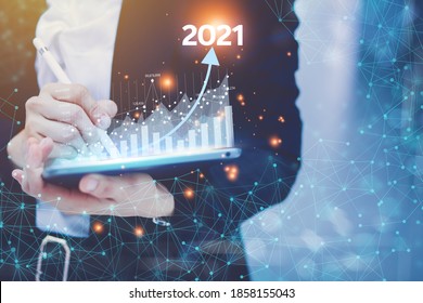 The concept of business people setting business goals Turn it into a 2021 concept by holding a virtual screen showing the 2021 year graph of trade growth and revenue.
 - Shutterstock ID 1858155043