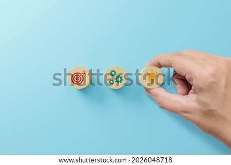 Concept of business strategy and action plan. Hand holding wood block with icon on blue background