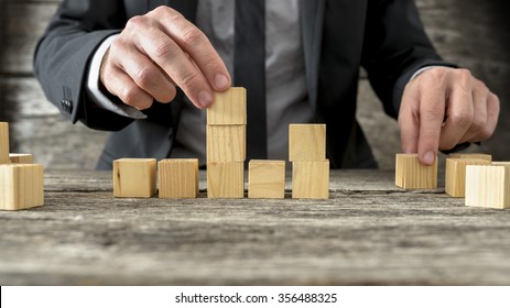 Concept of business strategy and planning - front view of male hand placing and positioning wooden blocks in various structures.