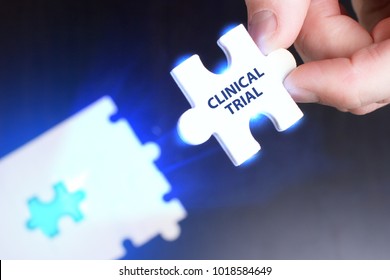 The Concept Of Business, Technology, The Internet And The Network. A Young Businessman Collects A Puzzle With The Proper Inscription: Clinical Trial