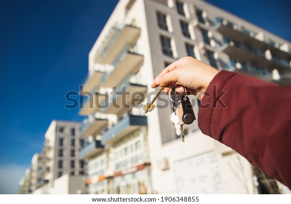 The concept of buying a new apartment.\
The woman hand holds the keys to a new\
apartment.