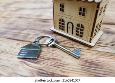 The concept of buying a new house or apartment. Rent, mortgage, real estate loan. Close-up of a toy wooden house with keys on a wooden background.