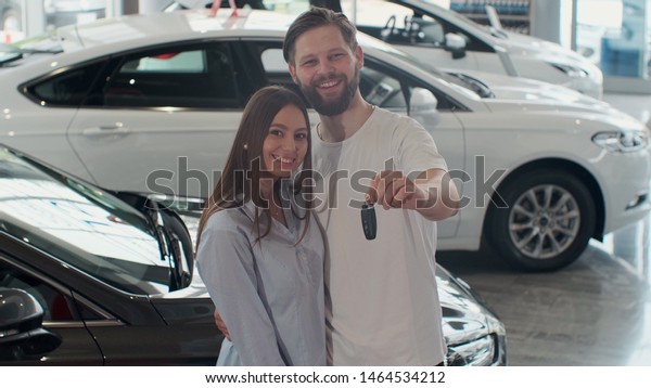 The concept of buying or renting a\
car. Young happy interracial couple with new car\
keys.