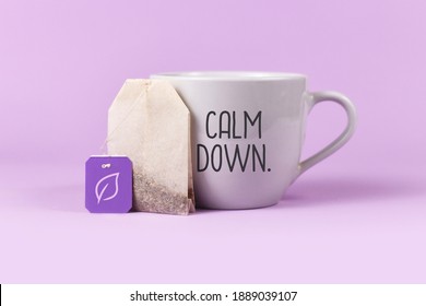 Concept For Calming Herbal Tea With Tea Bag With Leaf On Label Next To Tea Cup With Text 'Calm Down' On Violet Background