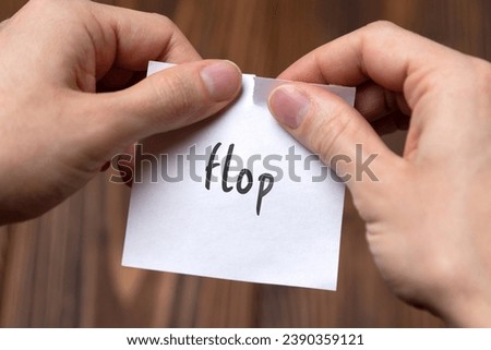 Concept of cancelling. Hands closeup tearing a sheet of paper with inscription flop