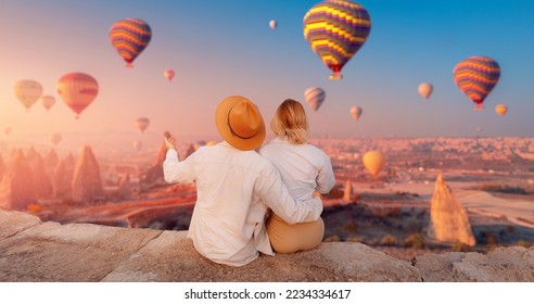 Concept Cappadocia Turkey travel. Happy traveler couple man and woman watching sunrise with hot air balloons in Kapadokya. - Shutterstock ID 2234334617