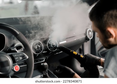The concept of car cleaning and detailing The detailing master cleans the car interior with a hot steam cleaner Cleaning car interior - Shutterstock ID 2278340871
