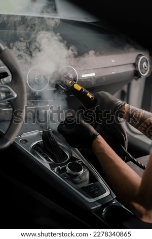 The concept of car cleaning and detailing The detailing master cleans the car interior with a hot steam cleaner Cleaning car interior