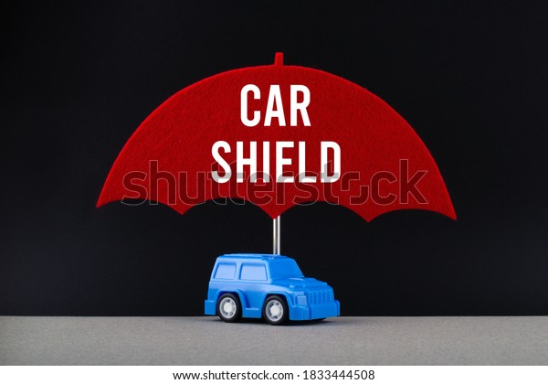 Concept of car insurance. Blue car under red\
umbrella with text Car\
shield