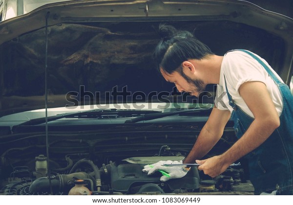 \
Concept of car\
maintenance in service stations : Side view male mechanic writes\
down the checklist for revision and verifies the scheduled use\
conditions and maintenance\
history.
