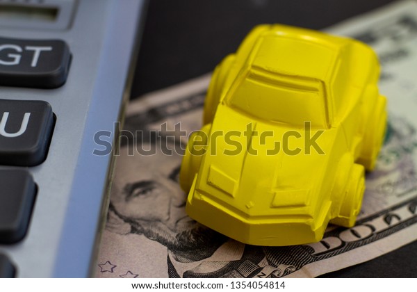 The concept of\
car rental, car bail, arrest of vehicles, car loan. Calculator,\
dollars and miniature\
vehicle.
