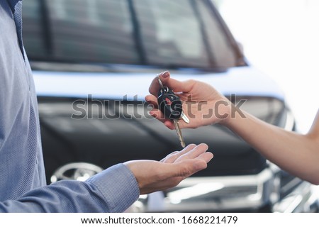 Concept car rental service. Close up view hands of agent giving car key to client that rent a vehicle  in rental office.