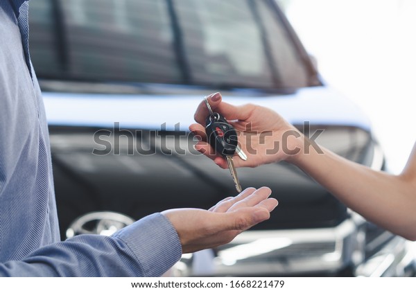 Concept car\
rental service. Close up view hands of agent giving car key to\
client that rent a vehicle  in rental\
office.