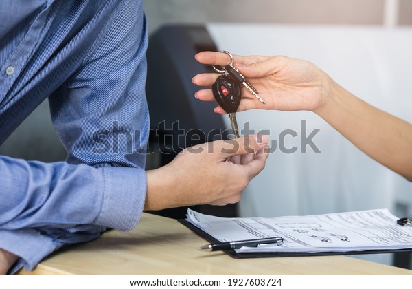 Concept car\
rental service. Close up view hands of agent giving car key to\
client that rent a vehicle  in rental\
office.