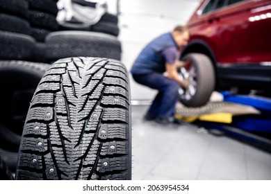 Concept car service replacement of winter and summer tires. Mechanic holding wheels at garage.