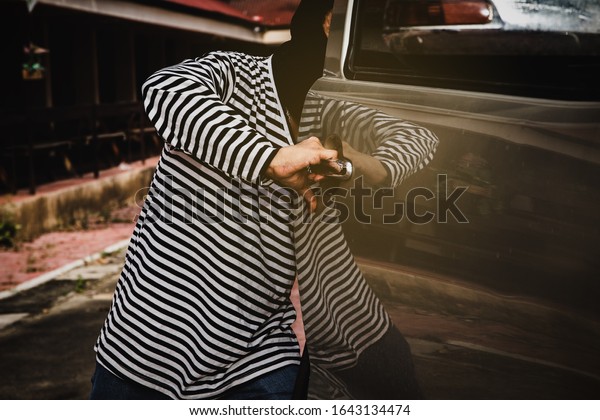 Concept of car theft : The male thief, using the\
bad skills to open the door of the pickup to steal the property and\
take the car\
